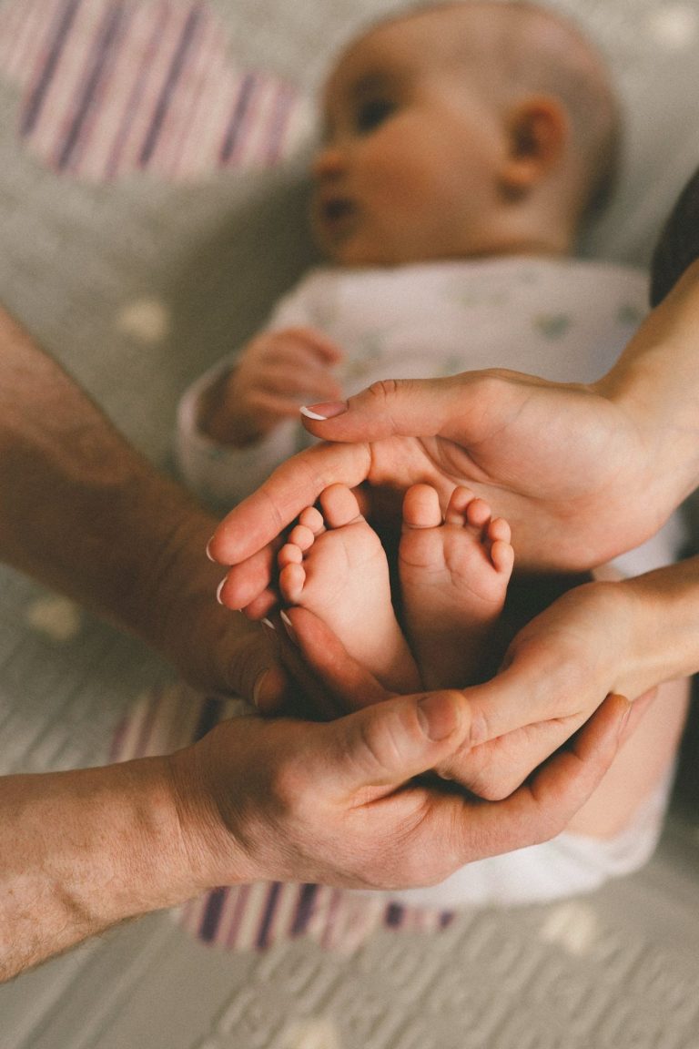 Les mains d'un papa et d'une maman tiennent les pieds de leur bébé