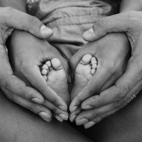 Des mains de parents entourent des pieds de leur bébé